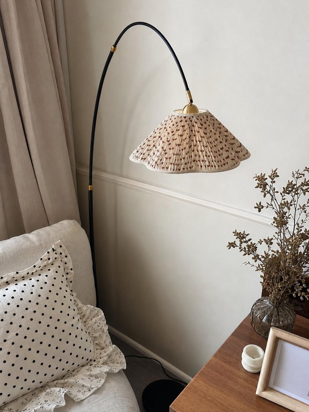 Florale zwanenhals vloerlamp naast een lage wand