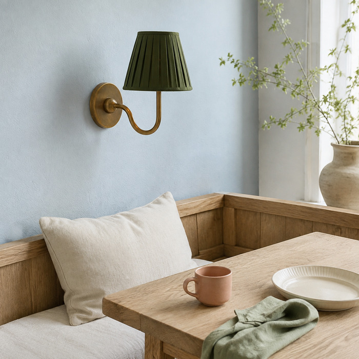 Groene, geplooide Baylor-wandlamp in een lichte ontbijthoek met licht eikenhouten meubels.