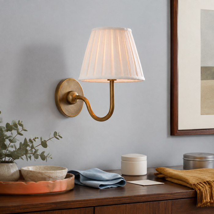 Geplooide messing wandlamp boven een console, schoongemaakt met een zachte doek en onderhoudsproducten.