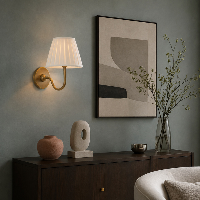 Een geplooide messing wandlamp, gecombineerd met abstracte kunst, keramiek en planten, in een moderne woonkamer.